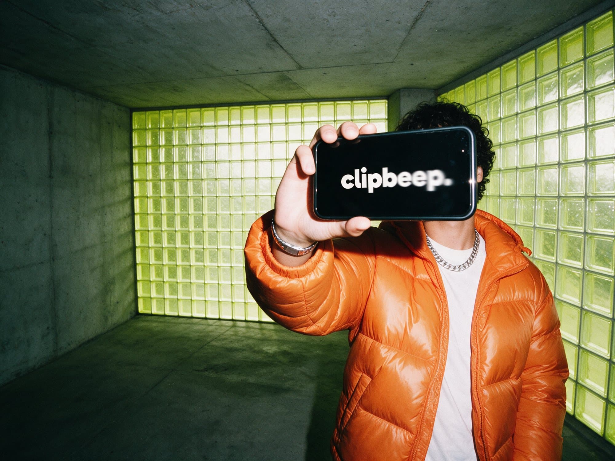 A creator holds up a phone showing the clipbeep logo